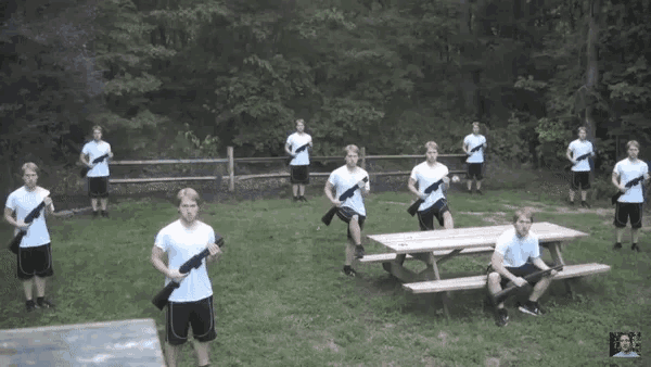 a group of young men are holding guns in a field in front of a picnic table
