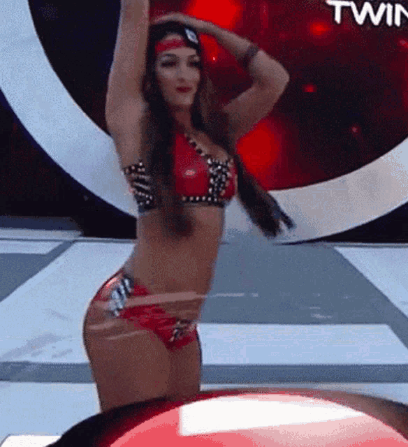 a woman in a bikini is dancing in front of a twin sign