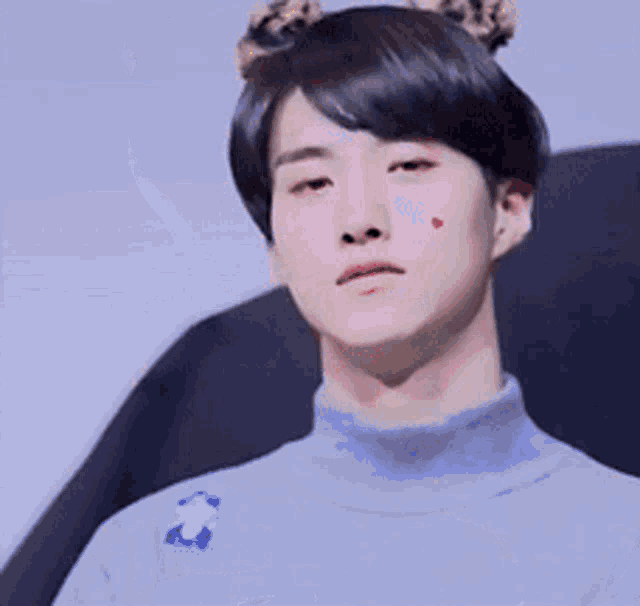 a young man with a heart on his cheek is wearing a blue sweater