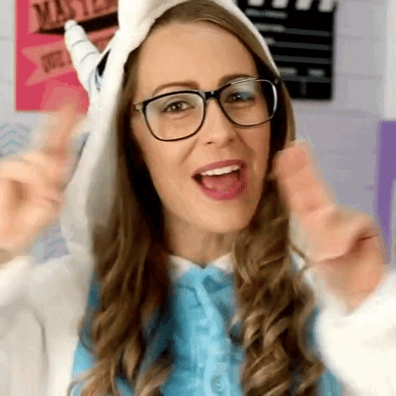 a woman wearing glasses and a unicorn hood is giving a thumbs up