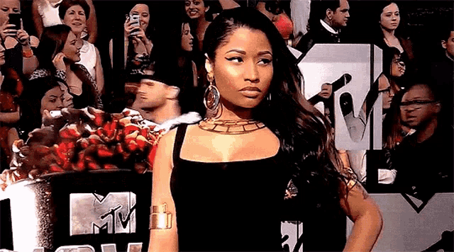a woman in a black dress is standing in front of a crowd at a mtv event .