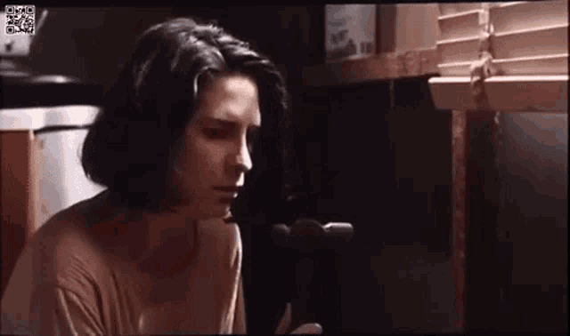 a woman is sitting in front of a window in a dark room holding a hammer .