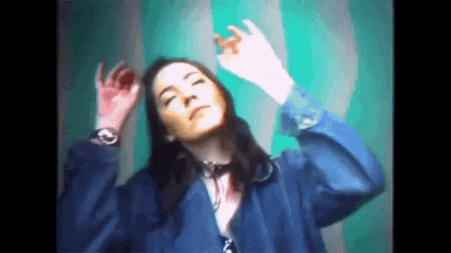 a woman in a blue jacket is dancing in front of a green and white curtain .