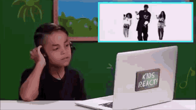 a boy wearing headphones is watching a video on a laptop that says kids react