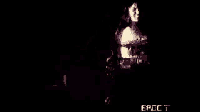 a woman is dancing in the dark on a stage in a video .