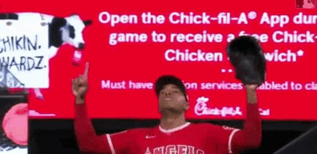a chick-fil-a sign is behind a baseball player holding up his glove