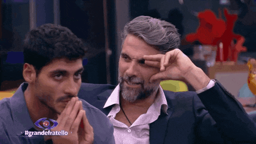 two men are sitting next to each other with the words grandefratello on the bottom