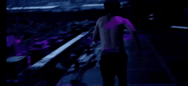 a man kneeling down on a stage with purple lights behind him