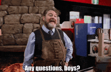 a man in an apron says any questions boys in front of a stone wall