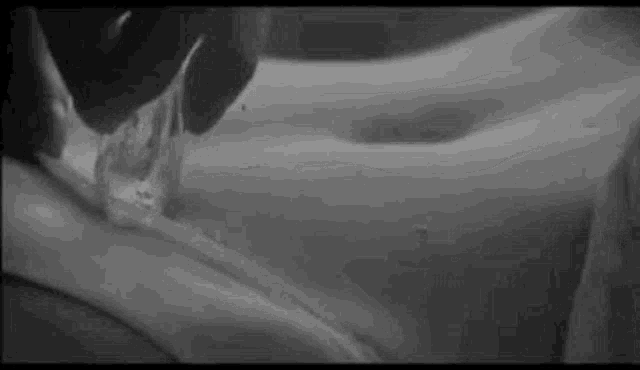a black and white photo of a person pouring liquid on another person 's stomach .