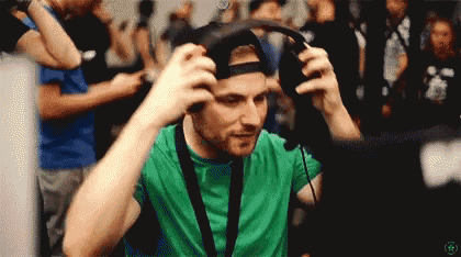 a man in a green shirt is wearing headphones and a lanyard around his neck