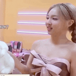 a woman in a strapless dress is holding a stuffed animal in her hands .