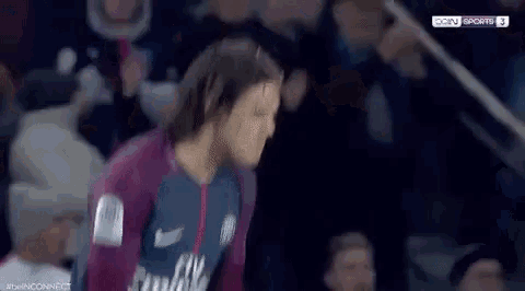 a man in a soccer uniform is standing in front of a crowd .