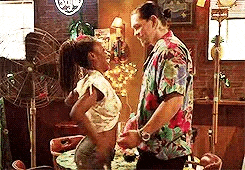 a man and a woman are dancing in a room with a fan .