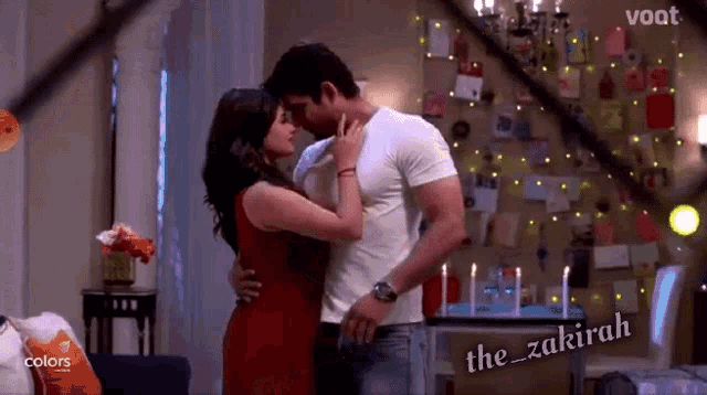 a man and a woman are kissing in a living room with candles on the wall ..