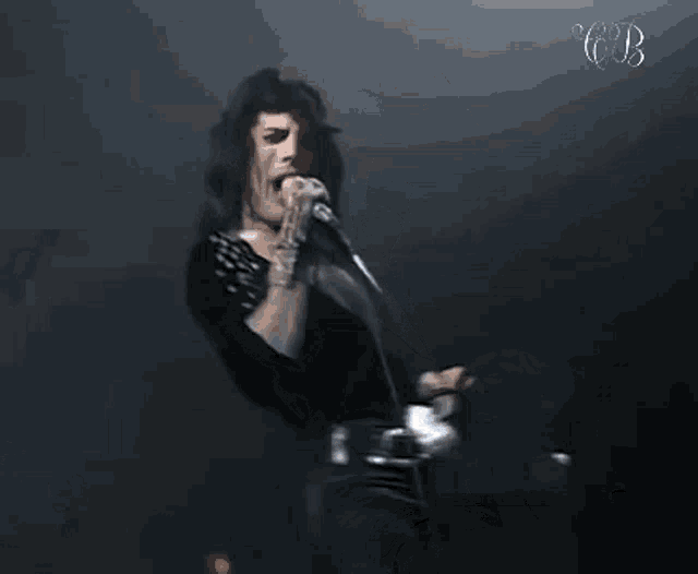 a man is singing into a microphone on a stage while holding a ball in his hand .
