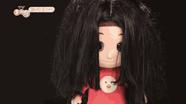 a doll with long black hair is wearing a red sweater with a duck on it .