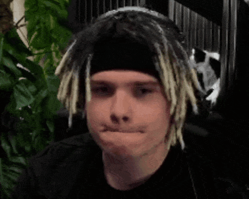 a man with dreadlocks is wearing a headband and a black shirt .