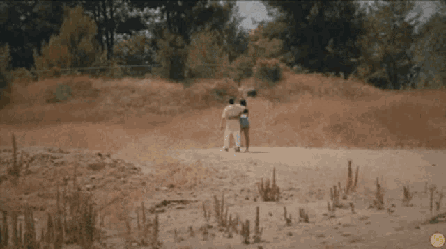 a man and woman are walking in a field with a yellow circle in the middle