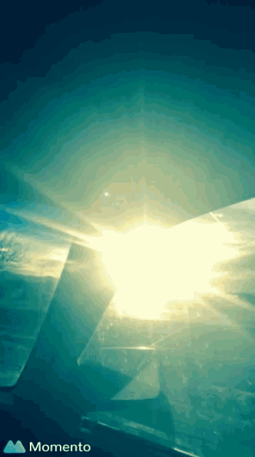 the sun is shining through the window of an airplane and the momento logo is visible