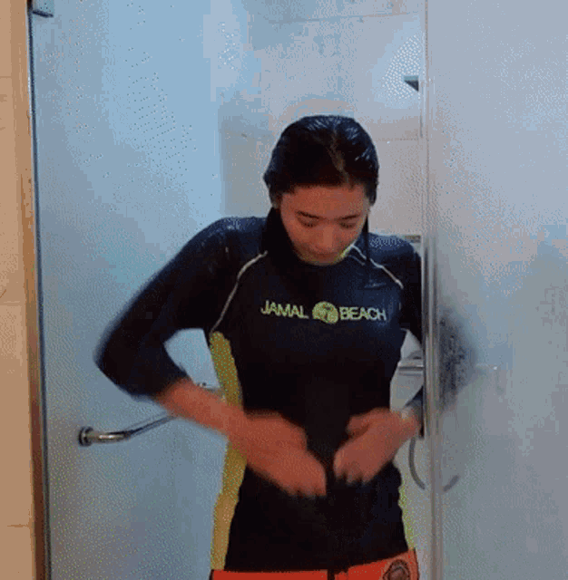 a woman in a jamal beach shirt is standing in a bathroom