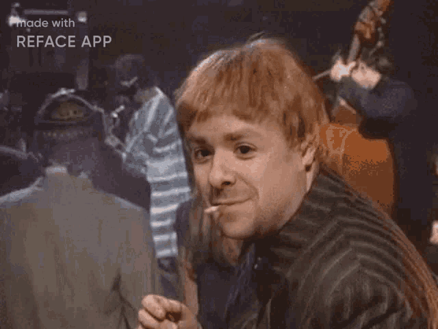 a man with red hair is giving the ok sign while standing in front of a group of people .