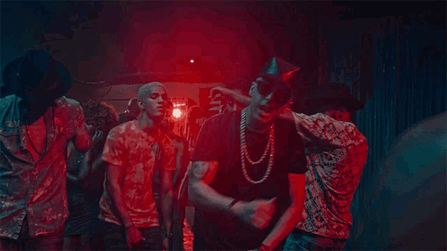 a group of young men are dancing in a dark room with red and blue lights