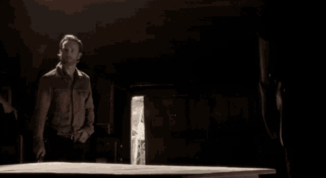 a man with a gun stands in front of a sign that says here we are