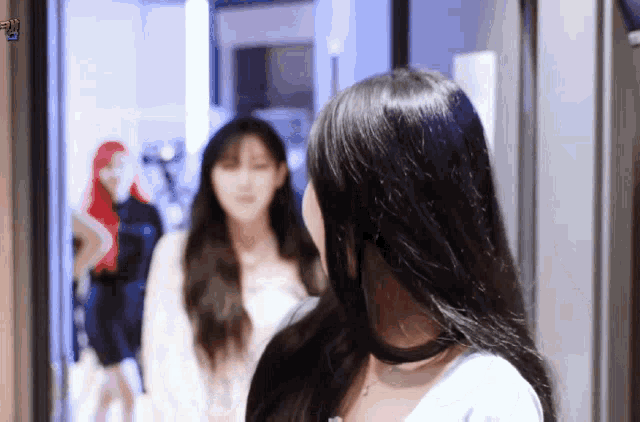 a woman with long black hair is standing in a doorway looking at the camera