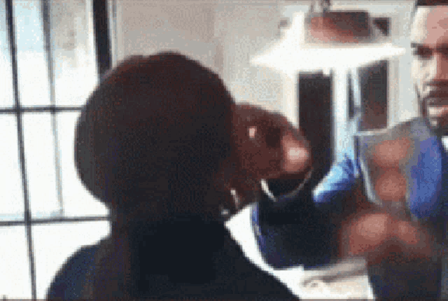 a man and a woman are having a conversation in front of a window . the woman is wearing hoop earrings .