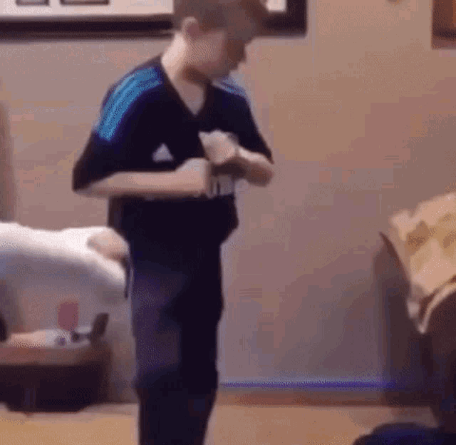 a young boy is standing in a living room playing a video game with a controller .