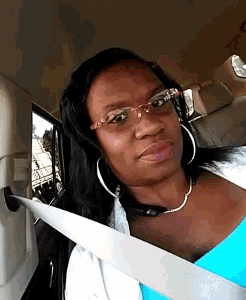 a woman wearing glasses is sitting in a car with a seat belt on