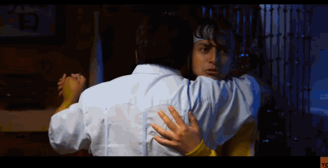 a man in a white shirt is holding another man 's arm