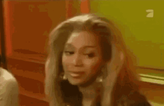 a woman is screaming with her mouth open in front of a yellow wall .