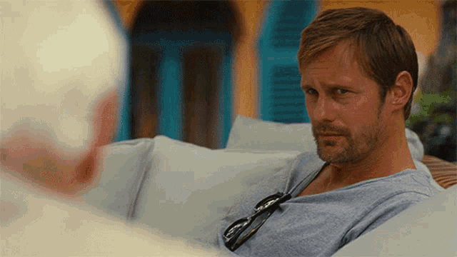 a man with a beard sits on a white couch