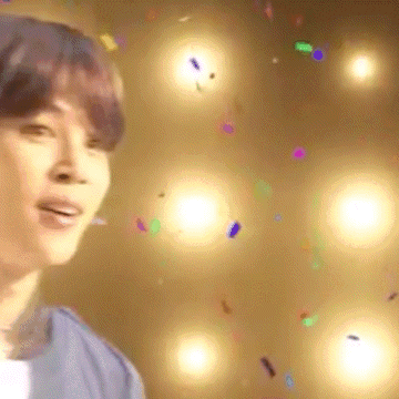 a man is standing in front of a wall of lights and confetti .