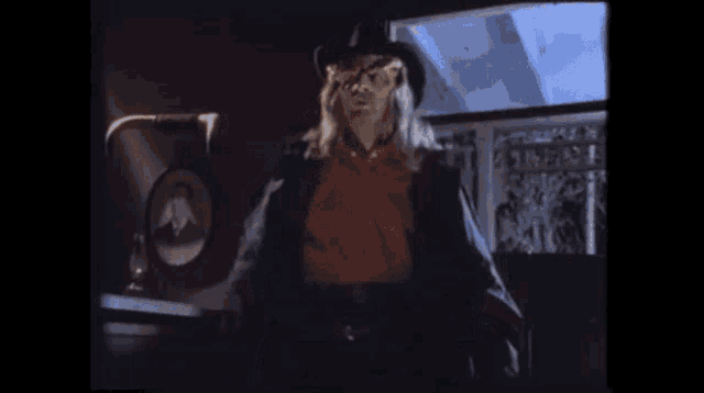 a man in a cowboy hat is standing in a dark room