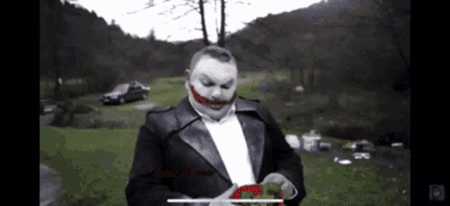 a man in a joker costume is holding a red object in his hand