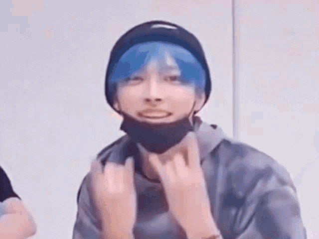 a person with blue hair is wearing a black hat and a mask .