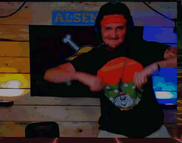 a man wearing headphones and an orange headband is dancing in front of a sign that says alse .