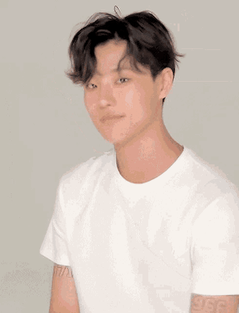 a young man wearing a white t-shirt has a speech bubble above his head that says ' korean ' on it