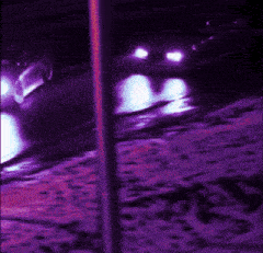 a car is driving down a road at night with purple lights