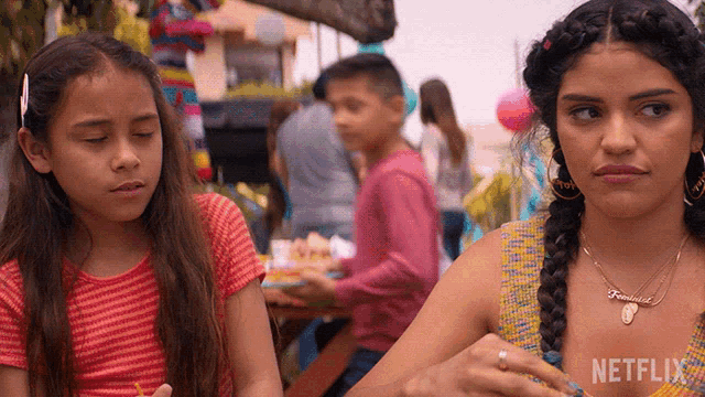two girls are sitting at a table with a netflix logo on the bottom right