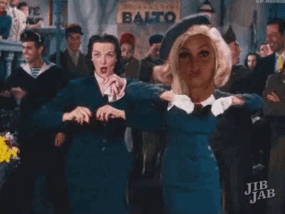 two women are dancing together in front of a crowd of people .