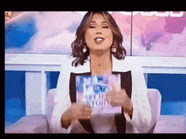 a woman in a white jacket is holding a book that says ' victoria '