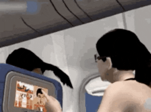 a woman is sitting on an airplane using a tv screen .