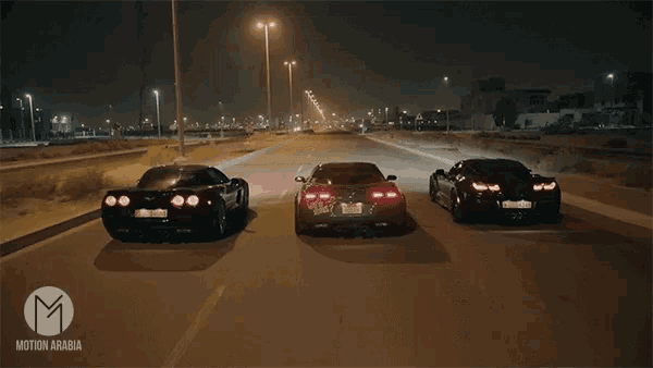three sports cars are driving down a highway at night with a motion arabia logo in the corner