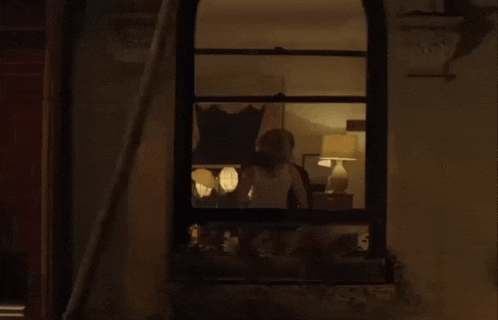 a window with a view of a bedroom with a bed and lamps .