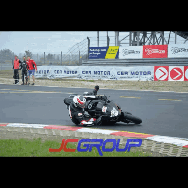 a man riding a motorcycle on a race track with jcgroup written on the bottom