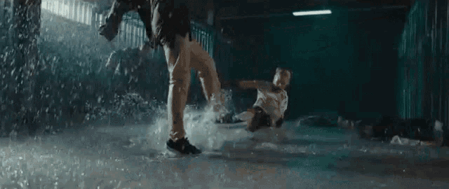 a man is jumping in the air in the rain while a woman is laying on the ground .